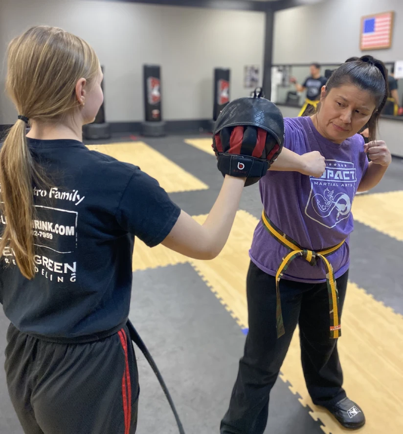 Adult martial arts students practicing self-defense techniques in Angola dojo